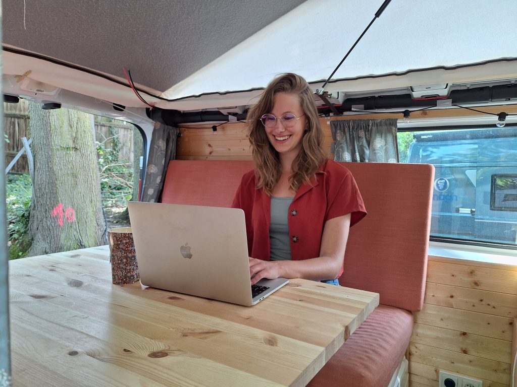 Foto van Lisa remote aan het werk in de bus met laptop op tafel
