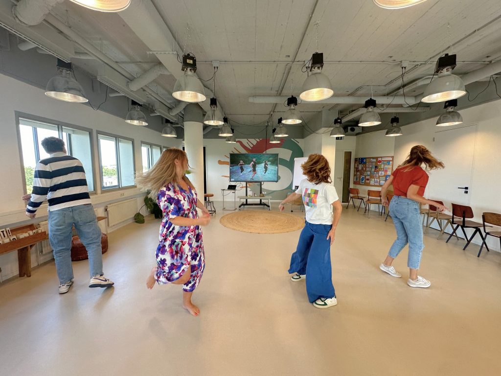Afbeelding waarop we met het team dansen op een video van Fitness Marshall, om aan meer beweging op werkdagen te komen